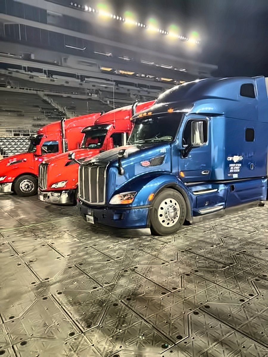 Blue CW Peterbilt parked inside a stadium at night