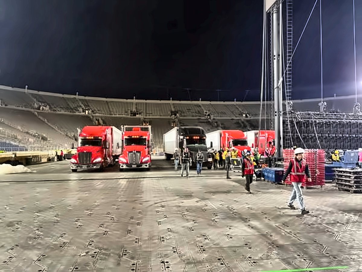 Stadium tour load-in with trucks, trailers and crew